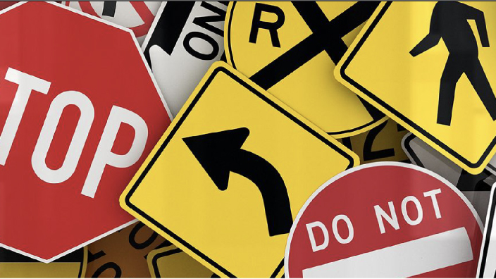 An assortment of road signs in yellow and red overlaying each other in a heap
