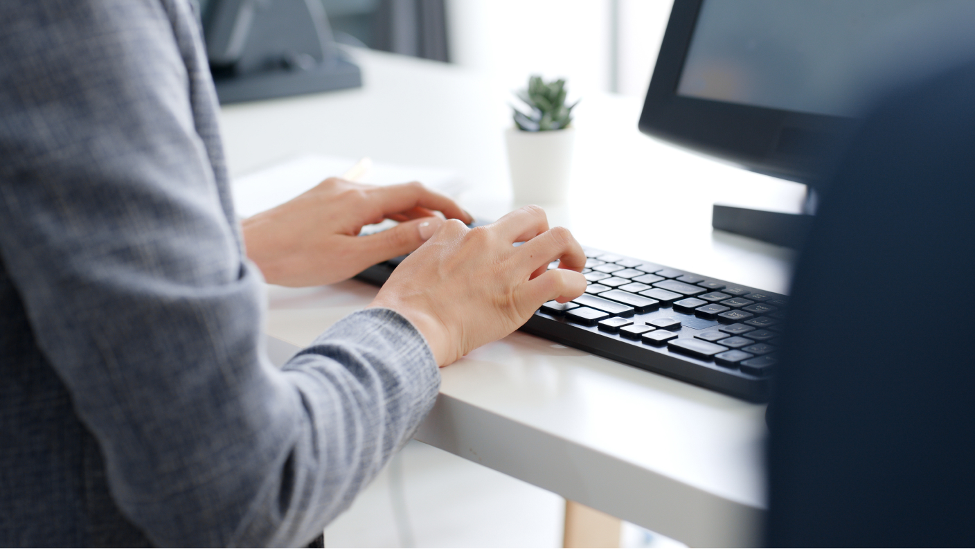 A person typing on a keyboard at a desk