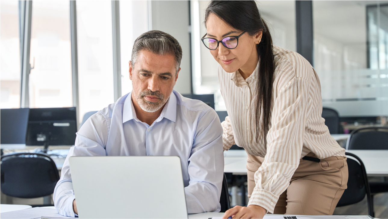 A woman and man in the office collaborating around a laptop