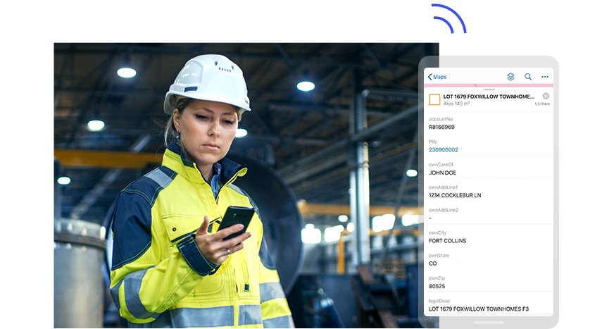 A person in a white hard hat and yellow safety jacket looking at a mobile phone held in their hand, beside a large graphic of a phone screen displaying a fictional person's account data