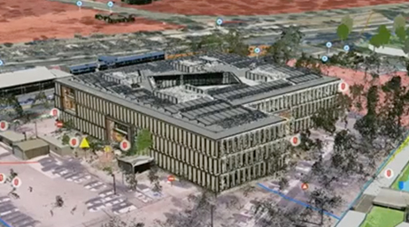 An aerial view of a 3D building model of a large hospital structure surrounded by parking lots and trees