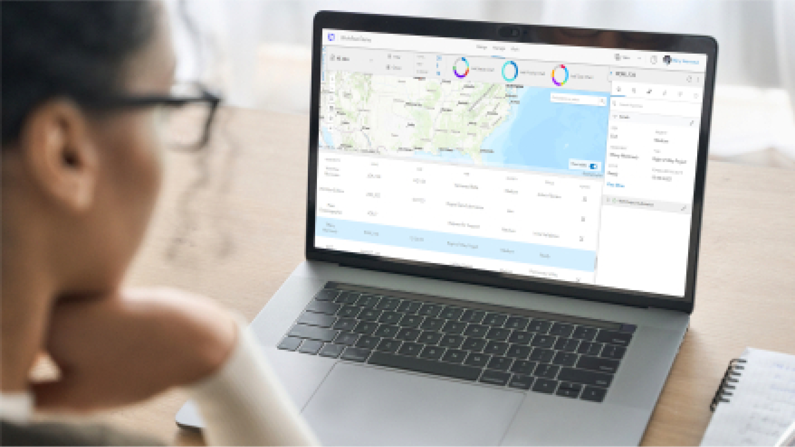 A person looking at their laptop displaying a project management system with a list of projects, job numbers, and a US map