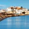A Greek city with white buildings on a waterfront 