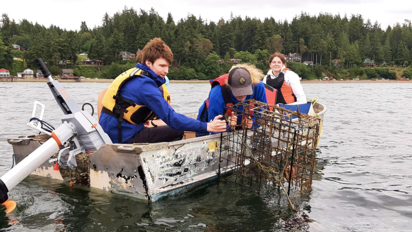 Three people on a small metal boat floating on a river