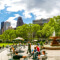 People walking through and sitting at tables near a fountain in Central Park