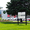 An exterior photo of the South Michigan Food Bank main entrance in red brick and blue wood beside a bright green lawn