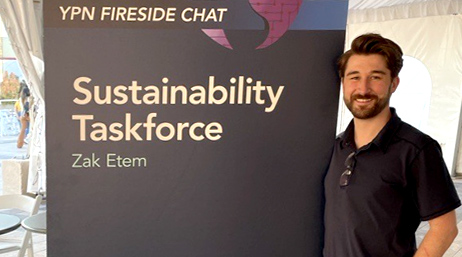 Zak Etem standing next to an event poster at the Esri User Conference