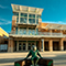 A statue of UNT’s eagle mascot in a green costume outside of a two-story brick campus building